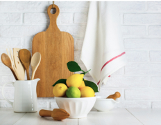 Lemons in a white bowl with a juicer and wooden cutting board in the background