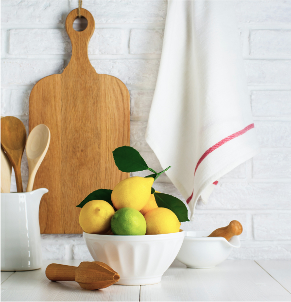 Lemons in a white bowl with a juicer and wooden cutting board in the background
