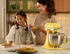 A person using a flour sifting attachment on a KitchenAid Color of the Year Artisan Stand Mixer