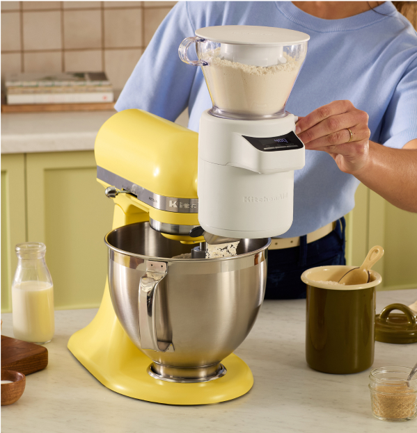 A person using a flour sifting attachment on a KitchenAid Color of the Year Artisan Stand Mixer