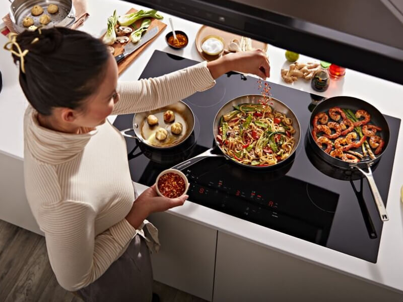 Person cooking on an electric cooktop Person cooking on an electric cooktop