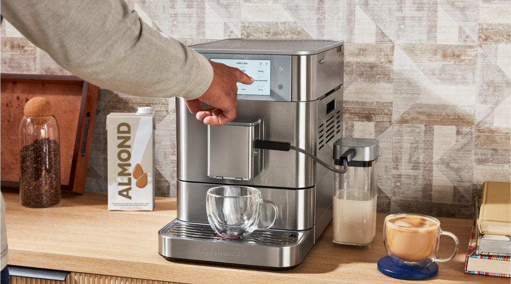 A person interacting with the touchscreen of a fully automatic espresso machine.