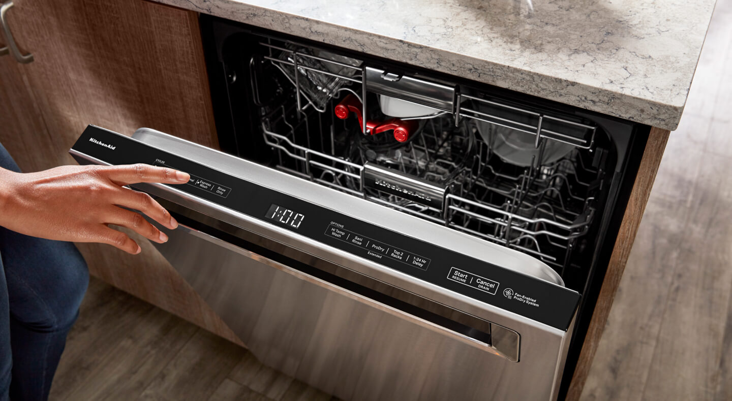A slightly ajar KitchenAid® top control built-in dishwasher with a pocket handle and third rack