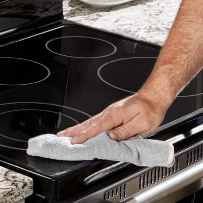 Hand using a dry towel to polish an induction cooktop
