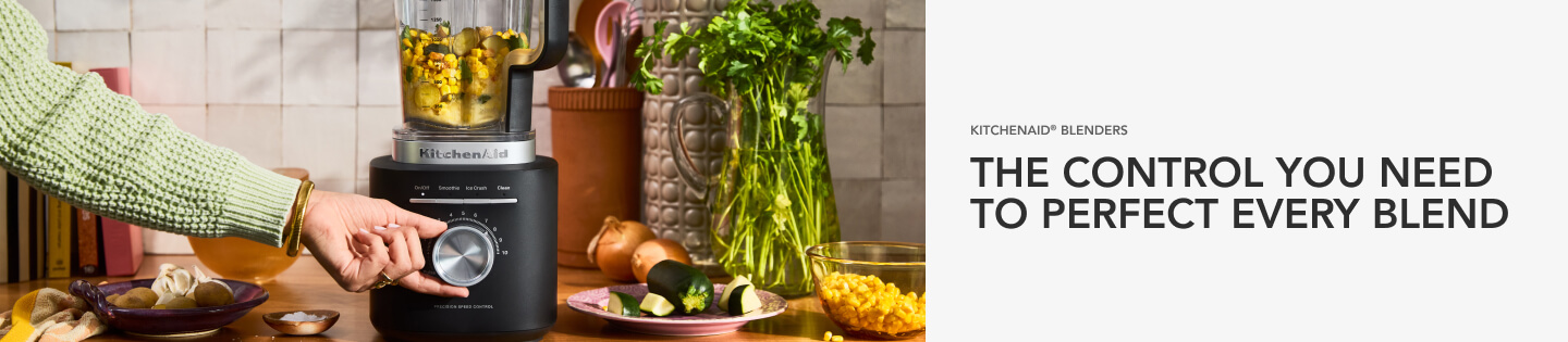 Hand turning the knob on a matte black KitchenAid®️ blender with salsa inside