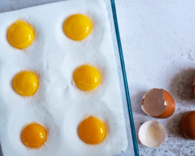 Egg yolks in a glass dish filled with salt