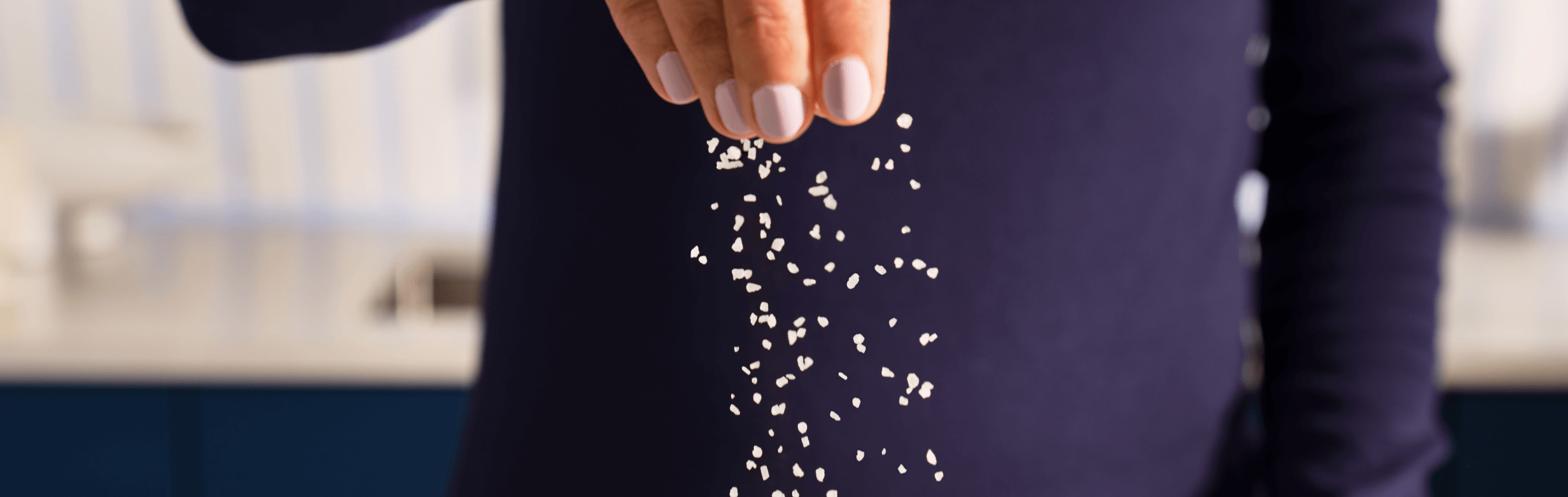 Person in a dark blue sweater sprinkling salt