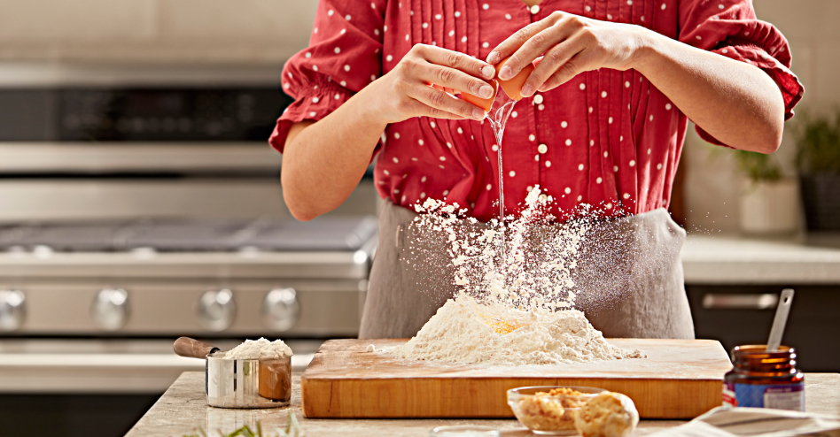 Baker cracking an egg over a bed of flour Baker cracking an egg over a bed of flour