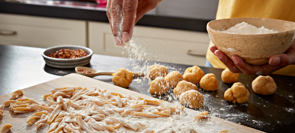 Hand sprinkling flour over fresh pasta Hand sprinkling flour over fresh pasta