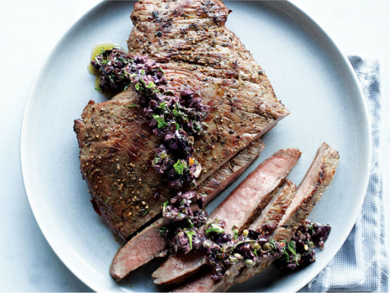 Sliced flank steak with a bright sauce on top