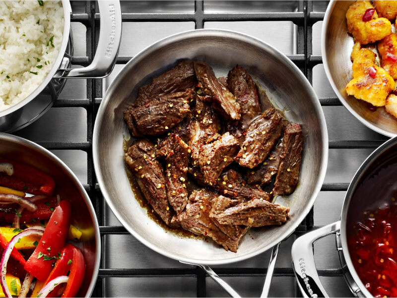 Sliced hanger steak cooking in a stainless steel pan