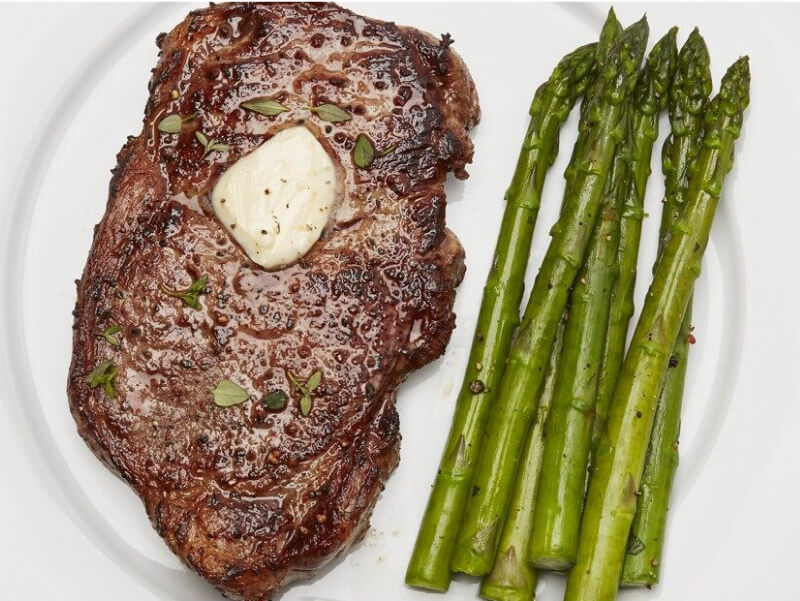 Juicy sirloin steak with a pad of butter and asparagus