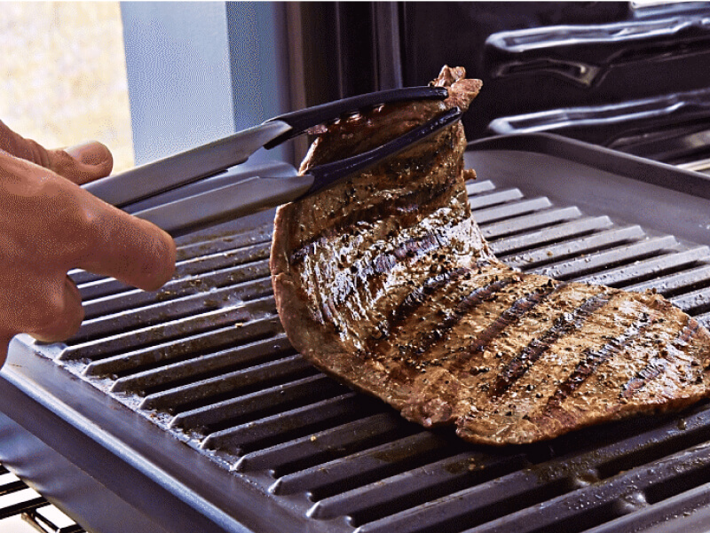 Person cooking a strip steak on their KitchenAid® smart oven grill attachment