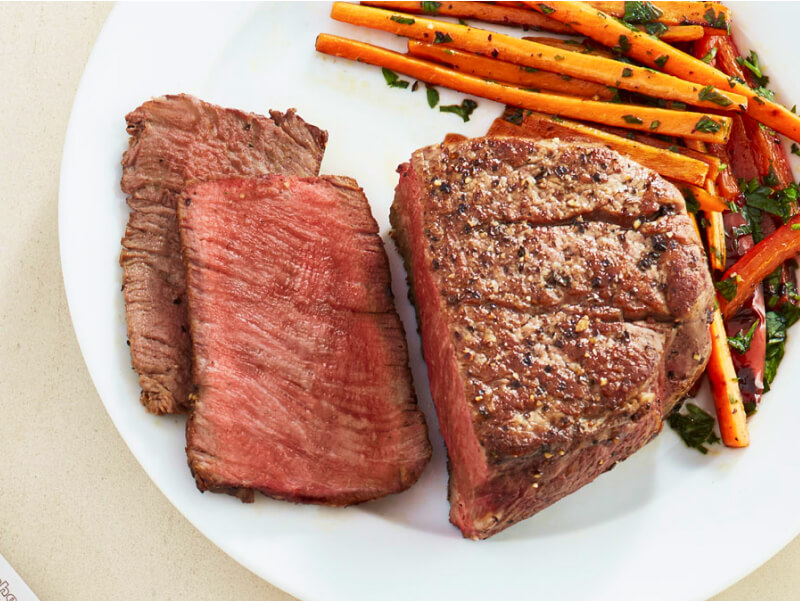 Sliced filet mignon on a plate with julienned carrots