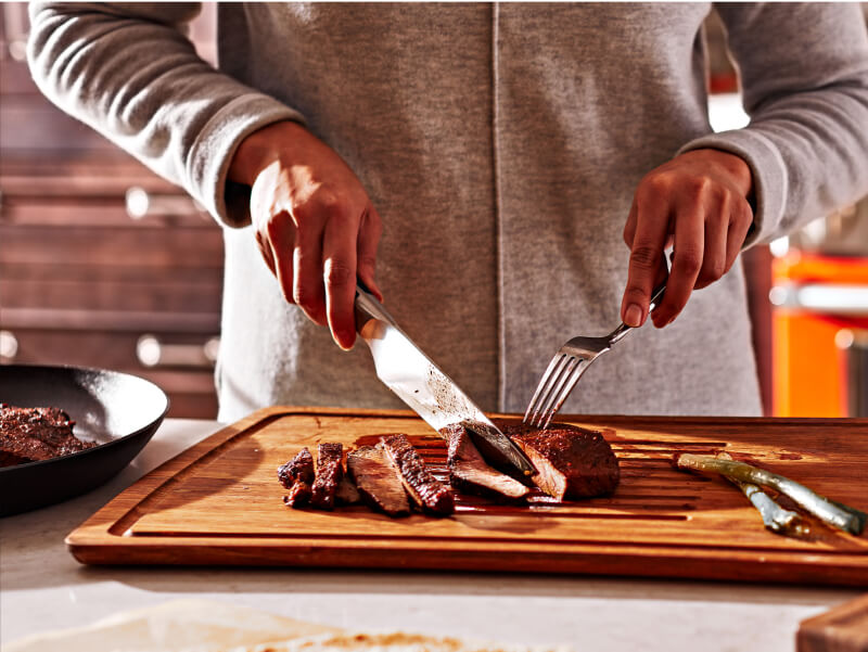 Person slicing a steak in their kitchen