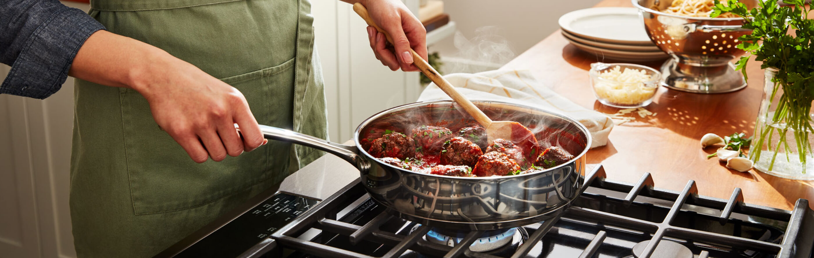A person preparing food in a pan on a gas cooktop