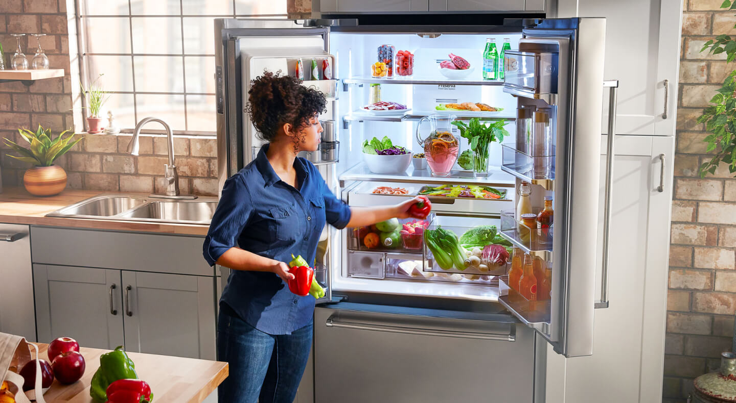 A person putting away fresh vegetables in a KitchenAid® french door refrigerator A person putting away fresh vegetables in a KitchenAid® french door refrigerator