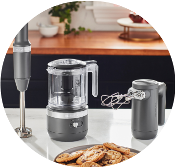 Matte Charcoal Grey KitchenAid® Cordless Immersion Blender, Food Chopper, and Hand Mixer on white countertop.