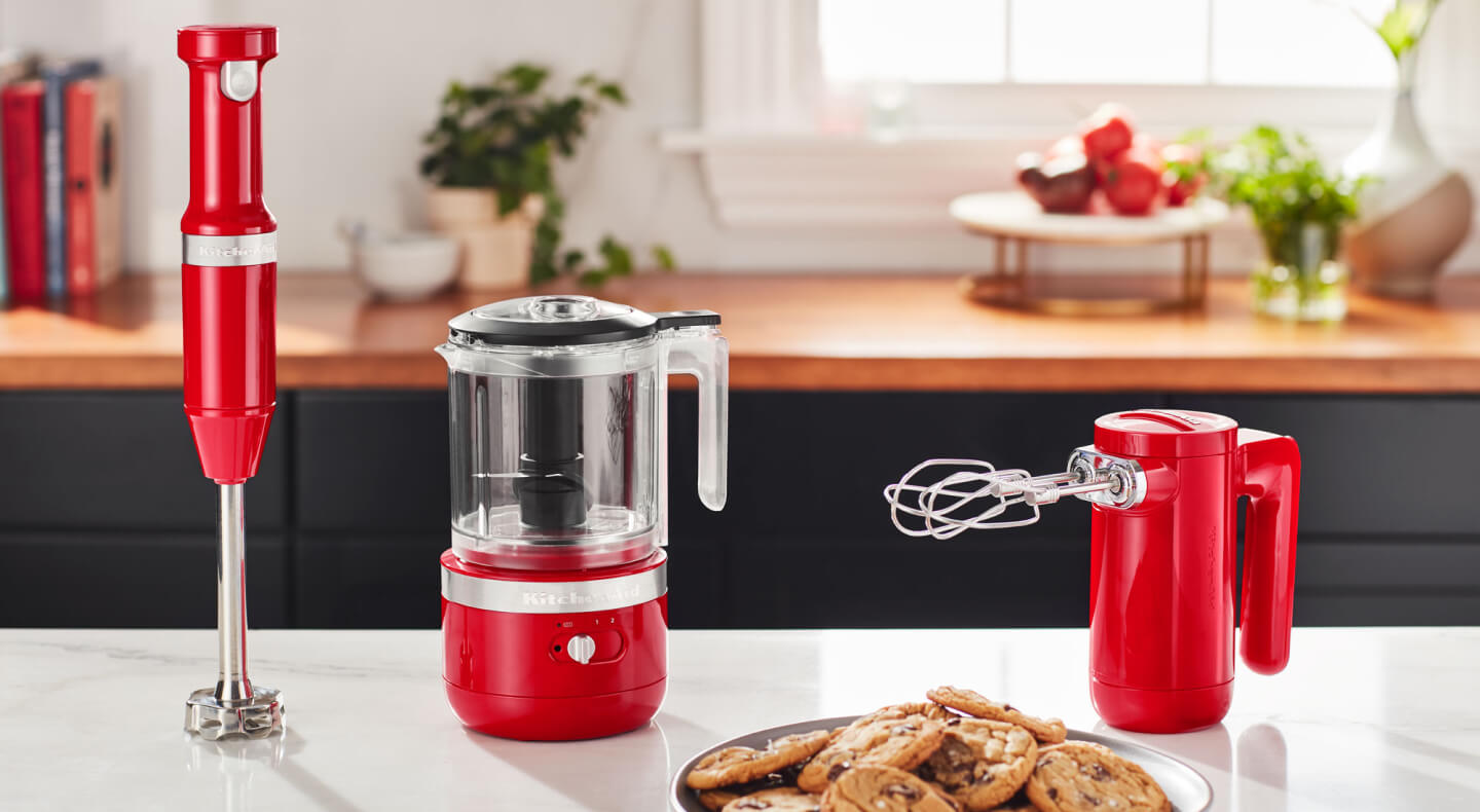 KitchenAid® red cordless hand blender, food chopper and hand mixer on a countertop KitchenAid® red cordless hand blender, food chopper and hand mixer on a countertop