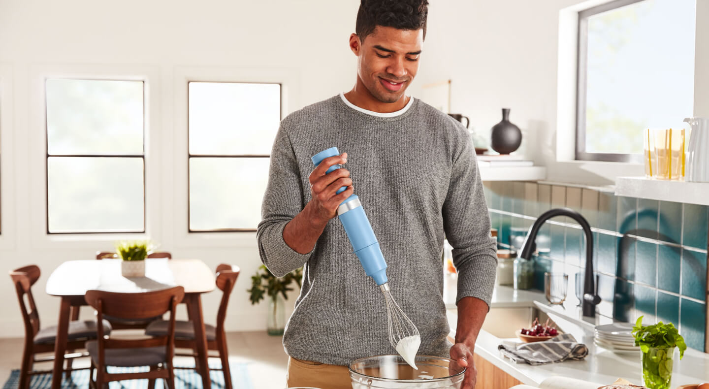 Person using a KitchenAid® cordless hand blender with whisk attachment Person using a KitchenAid® cordless hand blender with whisk attachment