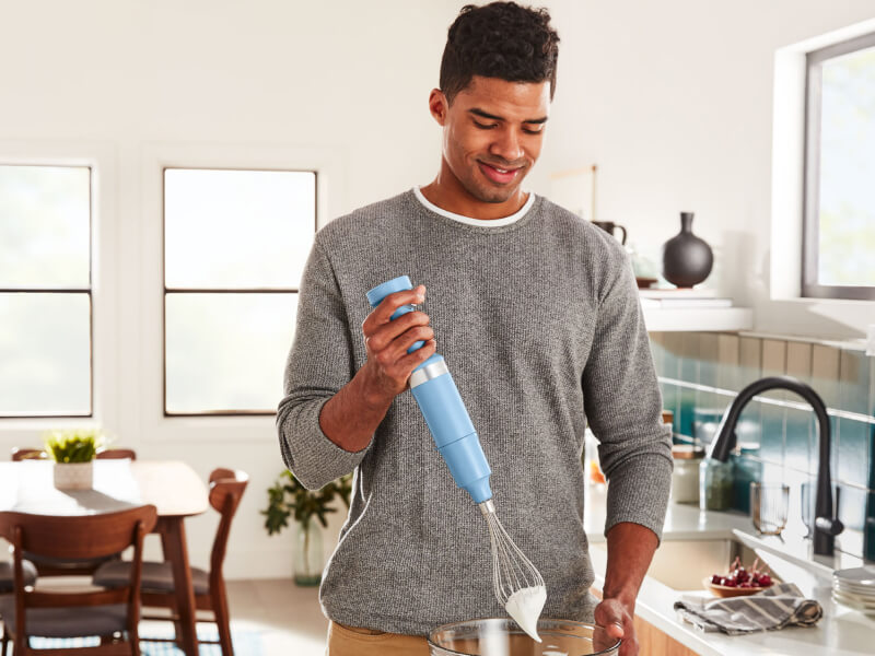 Person using a KitchenAid® cordless hand blender with whisk attachment Person using a KitchenAid® cordless hand blender with whisk attachment