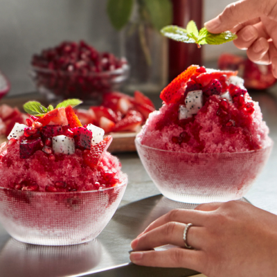 Shaved ice dessert garnished with fruit and mint