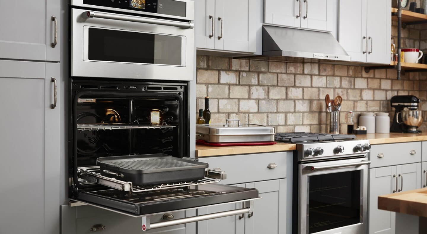 Open KitchenAid® wall oven with a rack holding a baking dish pulled out