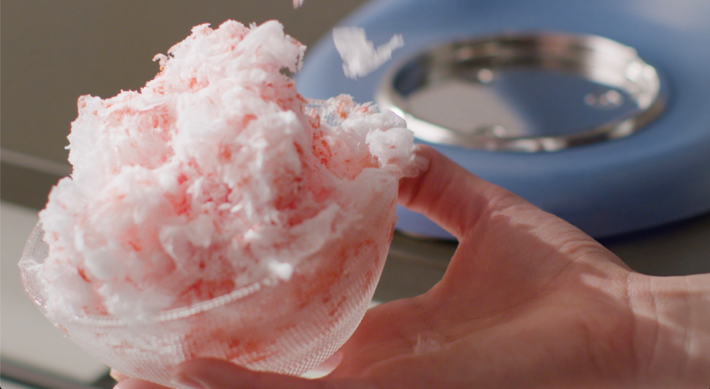 Bowl of shave ice dessert covered in pink syrup Bowl of shave ice dessert covered in pink syrup
