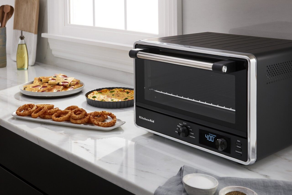 Air-fried onion rings on countertop next to KitchenAid® Countertop Oven with Air Fry.  Air-fried onion rings on countertop next to KitchenAid® Countertop Oven with Air Fry.