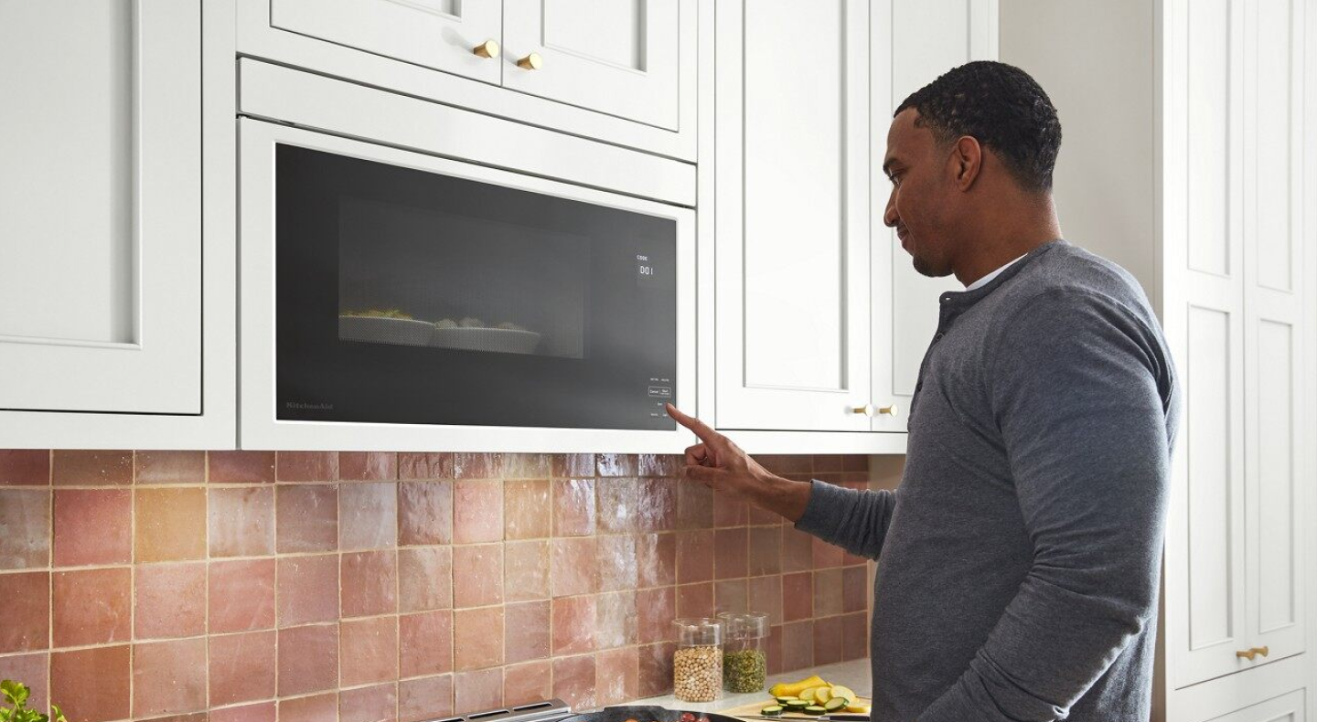 Person using a KitchenAid® over-the-range microwave