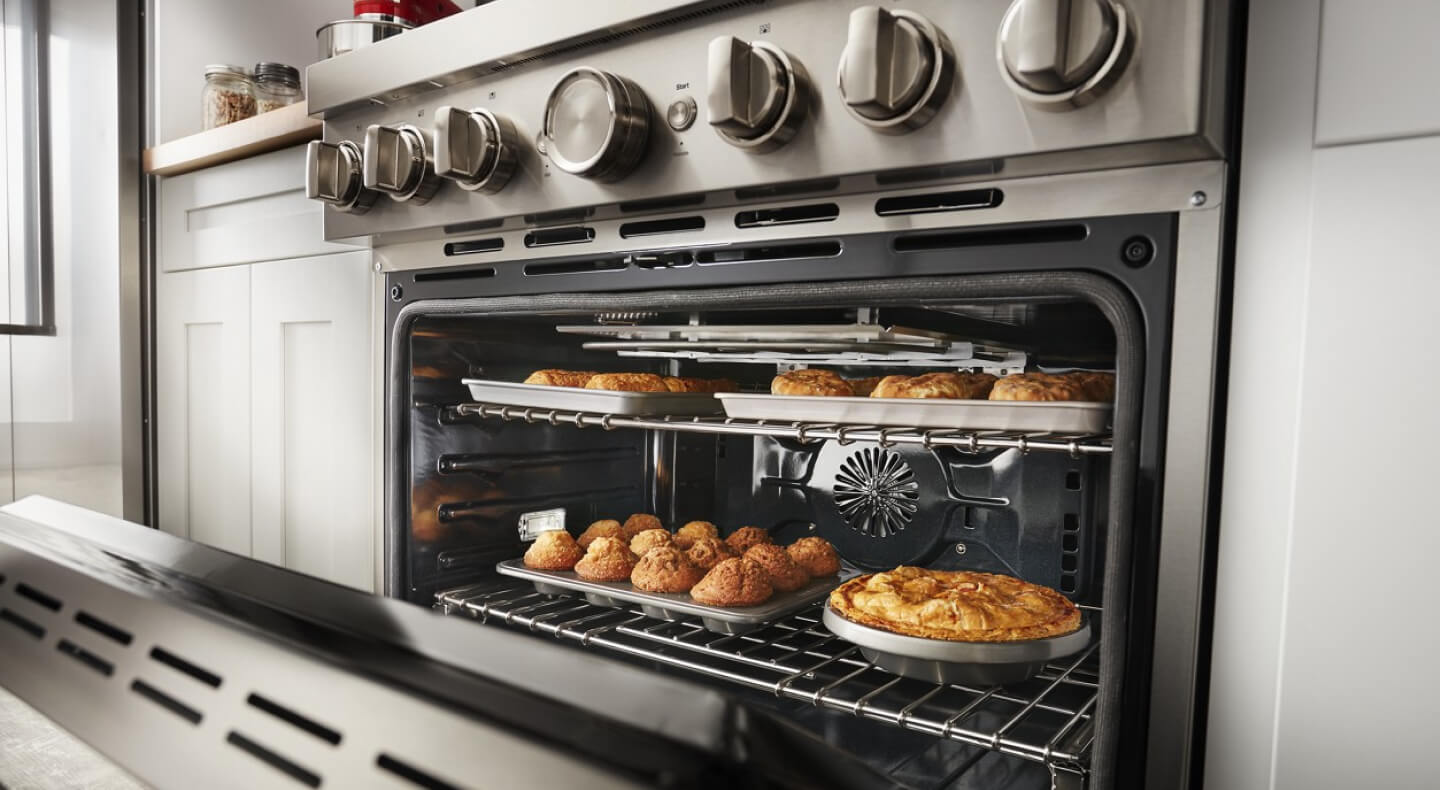 An open oven revealing baked goods on the top and bottom rack