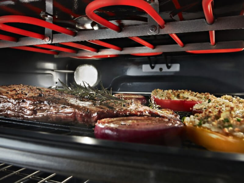 Close up image of meat and vegetables broiling in an oven