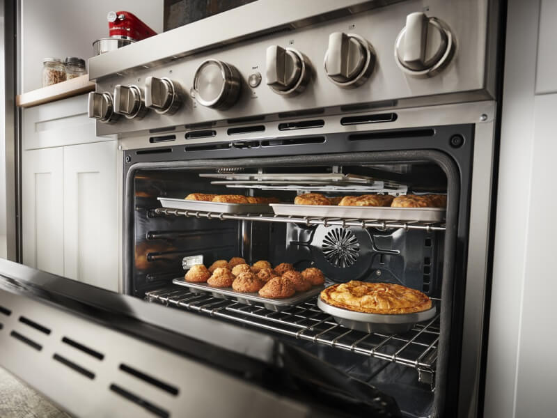 An open oven revealing baked goods on the top and bottom rack