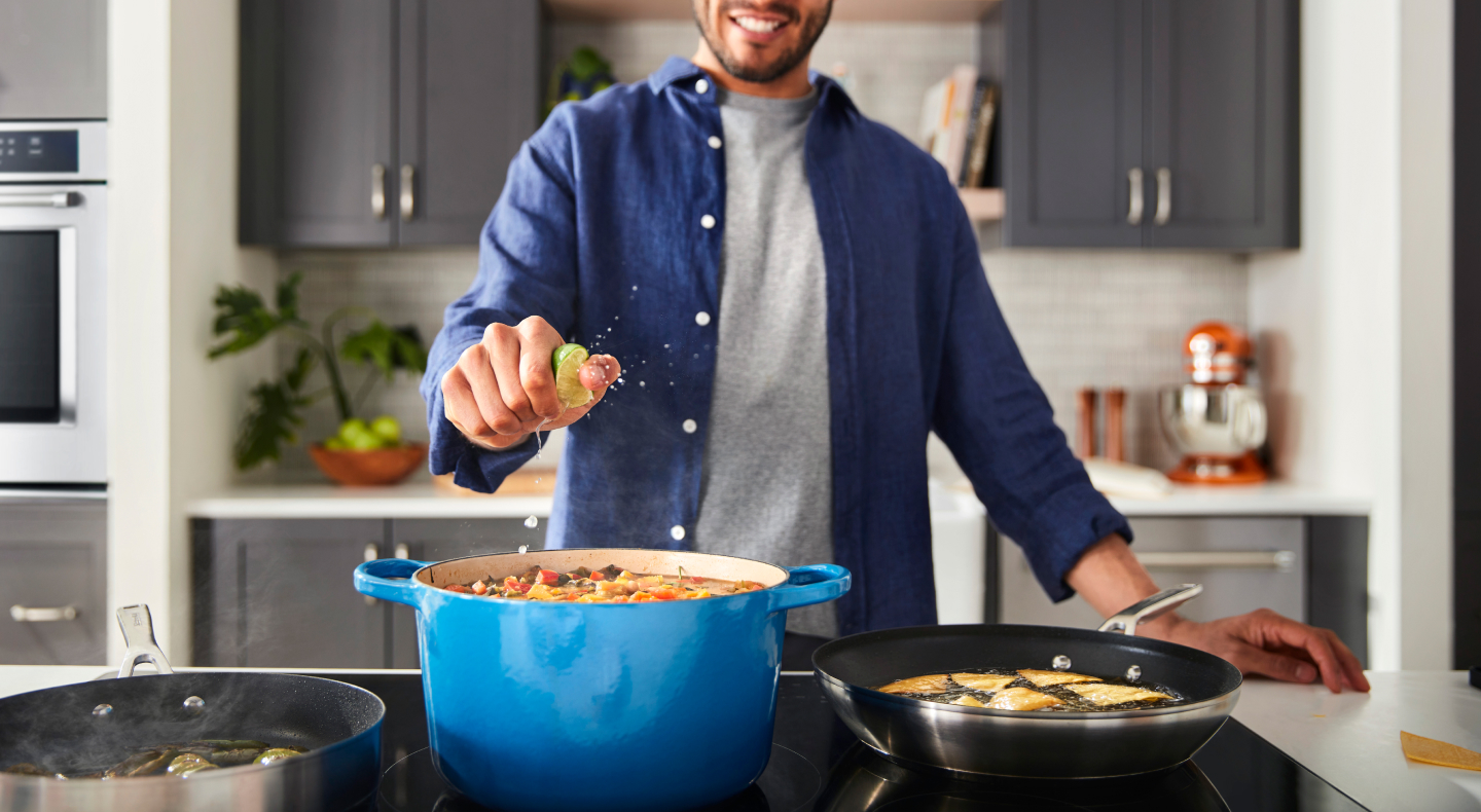 A man squeezing lime into a dish on a cooktop A man squeezing lime into a dish on a cooktop