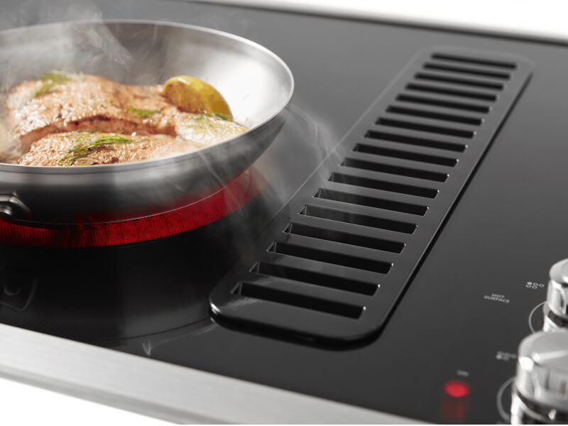 Food cooking on KitchenAid® induction cooktop with downdraft ventilation