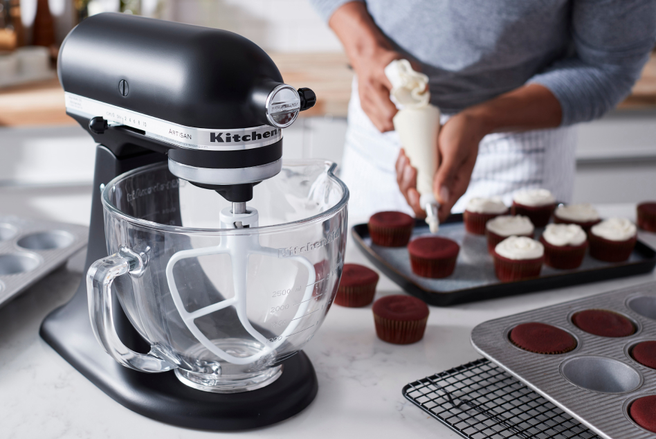 A black stand mixer with a glass bowl and red velvet cupcakes. A black stand mixer with a glass bowl and red velvet cupcakes.