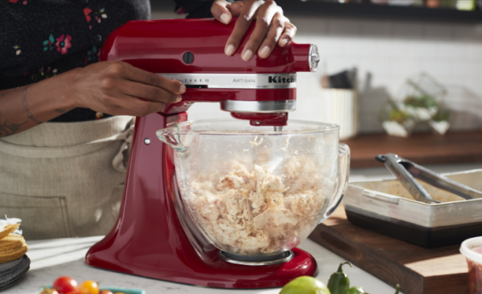 Woman operating a red stand mixer to shred chicken Woman operating a red stand mixer to shred chicken