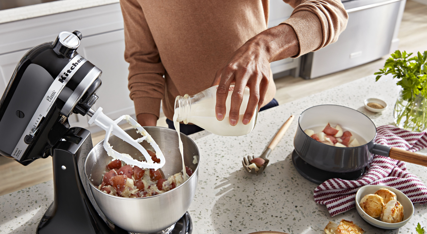 Person pouring milk into a KitchenAid® stand mixer bowl Person pouring milk into a KitchenAid® stand mixer bowl