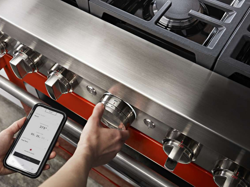 Person turning knob and monitoring smart range on the app Person turning knob and monitoring smart range on the app