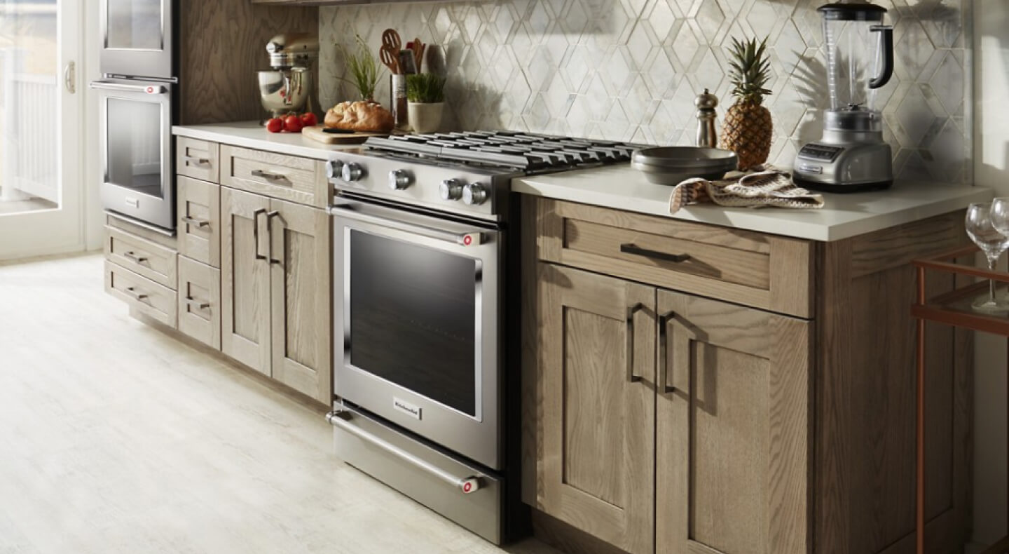 Stainless steel KitchenAid® gas range in modern brown cabinetry