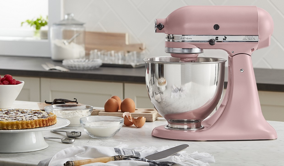 Pink Artisan® Series Stand Mixer on a countertop surrounded by cooking ingredients Pink Artisan® Series Stand Mixer on a countertop surrounded by cooking ingredients