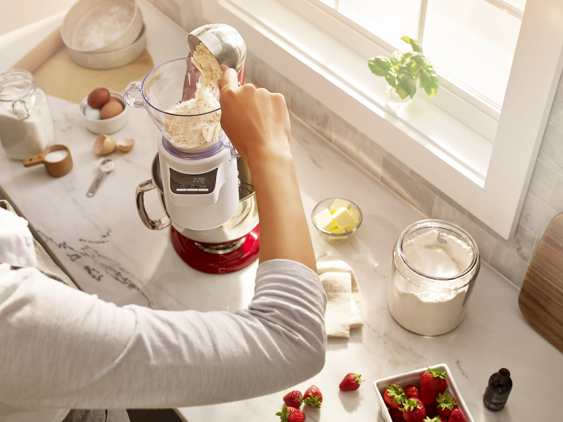 A person pouring flour into KitchenAid® Sifter & Scale Attachment. A person pouring flour into KitchenAid® Sifter & Scale Attachment.