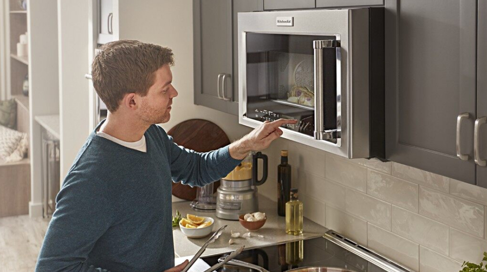Man standing in front of an over-the-range microwave Man standing in front of an over-the-range microwave