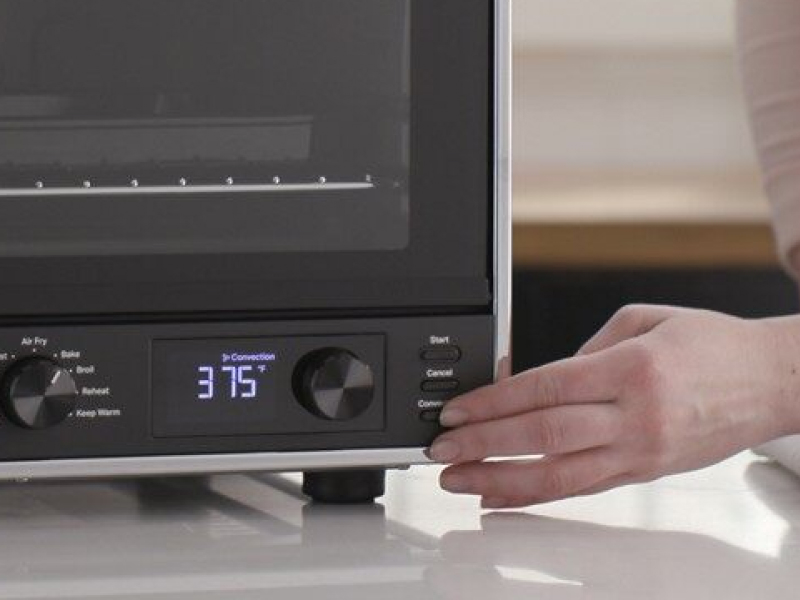 Person selecting a setting on a countertop oven
