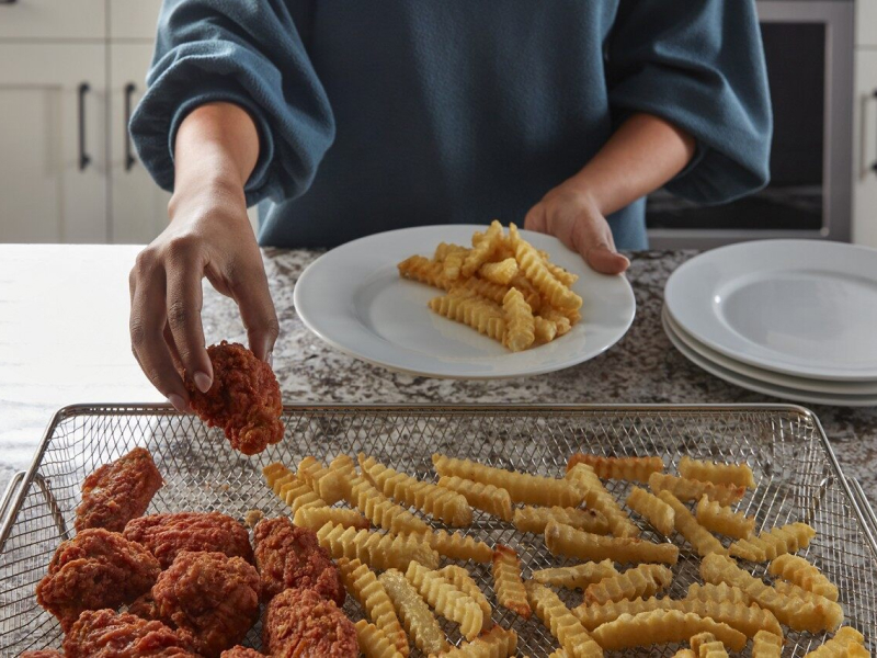 Person removing food from an air fry basket