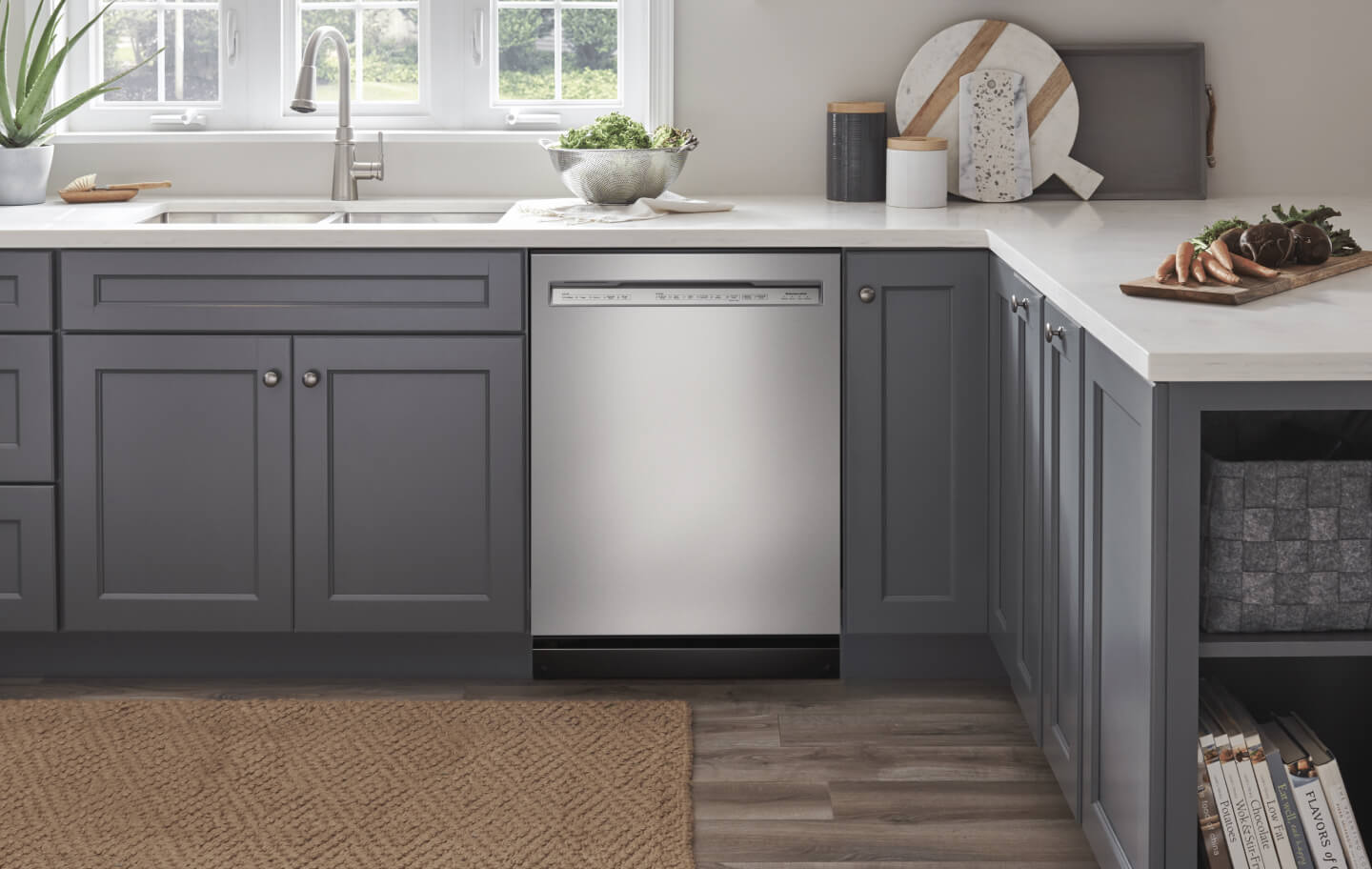 Stainless steel front control dishwasher next to gray cabinets