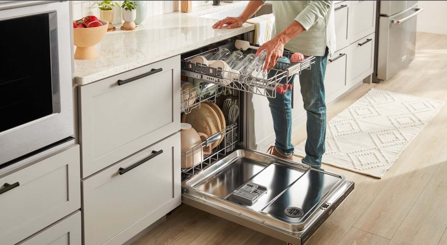 Person loading a KitchenAid® dishwasher