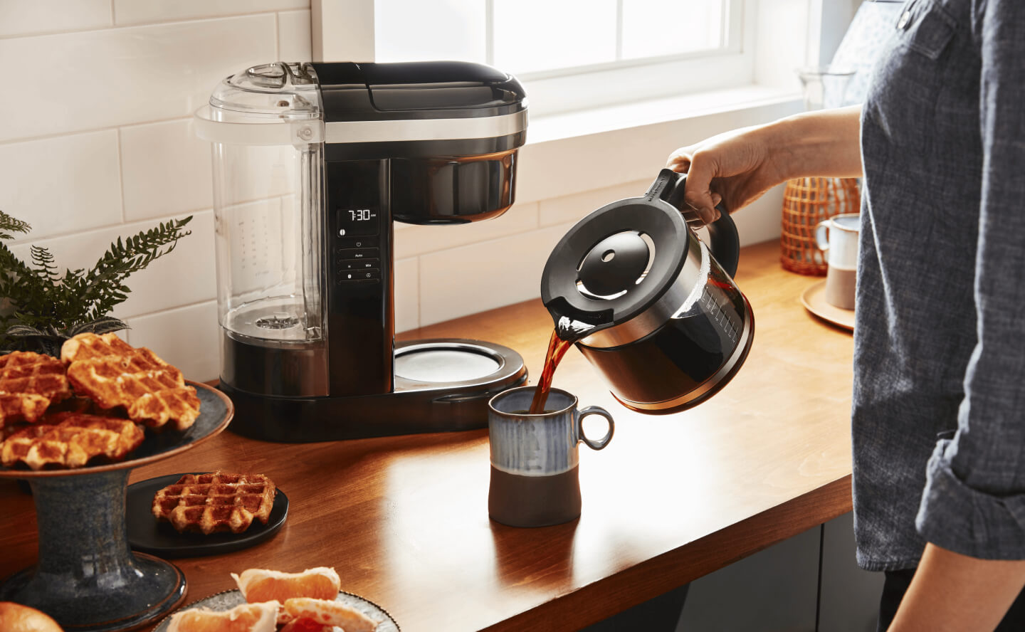 Person pouring coffee from a coffee pot into a mug