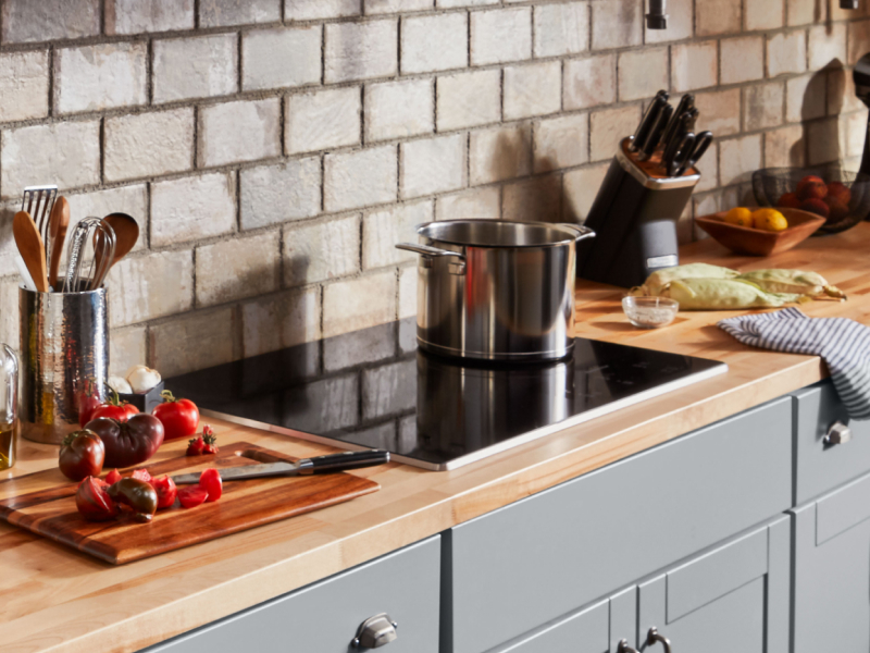 Pot resting on cooktop with sliced vegetables to the side Pot resting on cooktop with sliced vegetables to the side