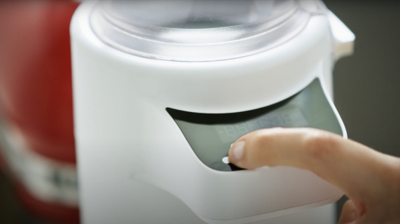 A person using the Sifter+Scale Attachment from KitchenAid brand.